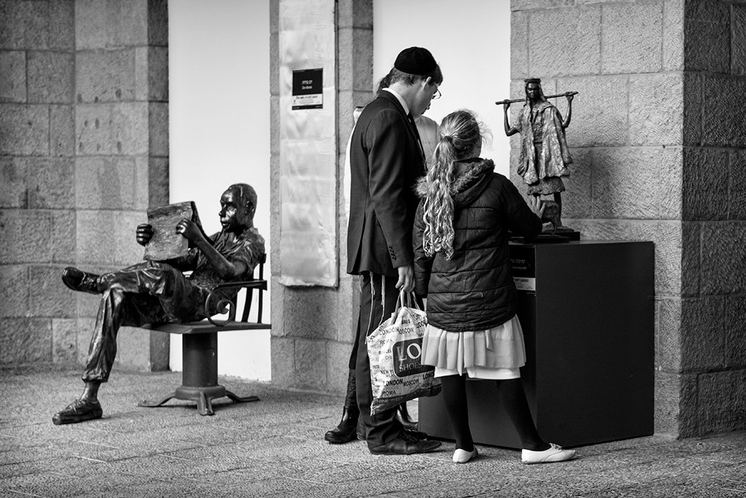 Two people beside sculptures in a space with stone columns.